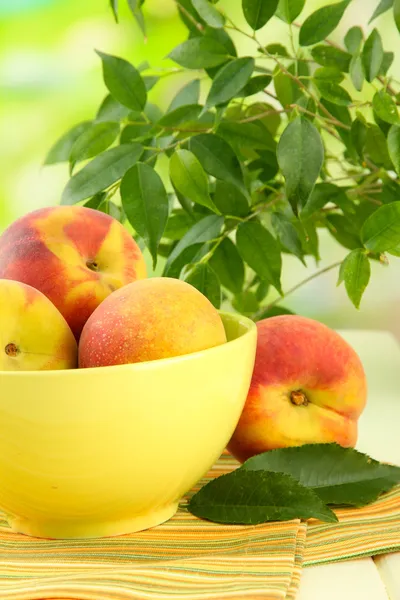 Ripe sweet peaches on table in bowl, outdoors — Stock Photo, Image