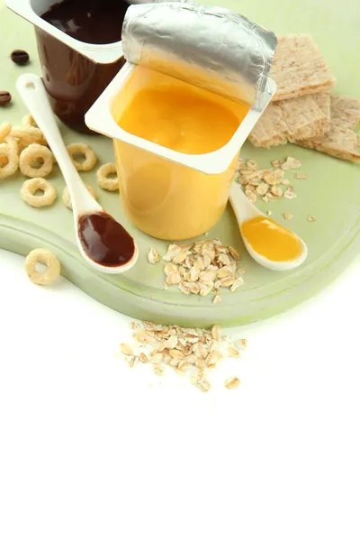 Smaskiga desserter i öppna plastkoppar och honung kammar, frukt och flingor på träplatta isolerad på vit — Stockfoto