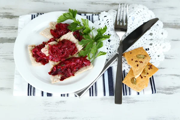 Beet salad on toasts on plates on wooden table — Stock Photo, Image