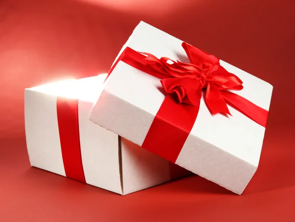 Caja de regalo con luz brillante sobre fondo rojo — Foto de Stock