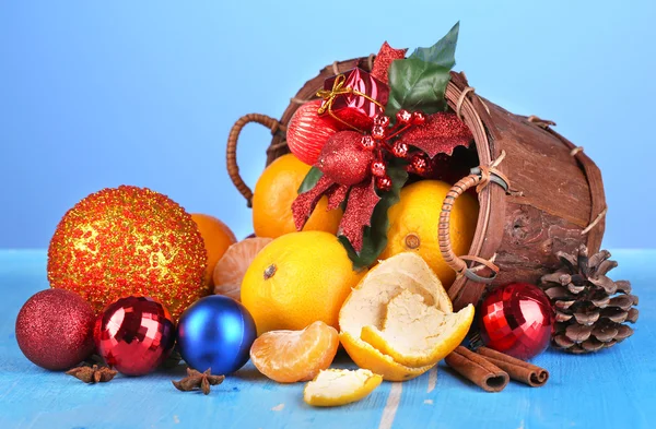 Boże Narodzenie mandarynki i Boże Narodzenie zabawki w kosz na drewnianym stole na niebieskim tle — Zdjęcie stockowe