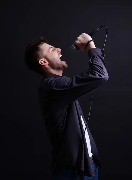 Jovem músico cantando, em fundo cinza — Fotografia de Stock