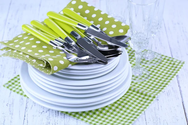 Sauberes Geschirr auf Holztisch auf hellem Hintergrund — Stockfoto