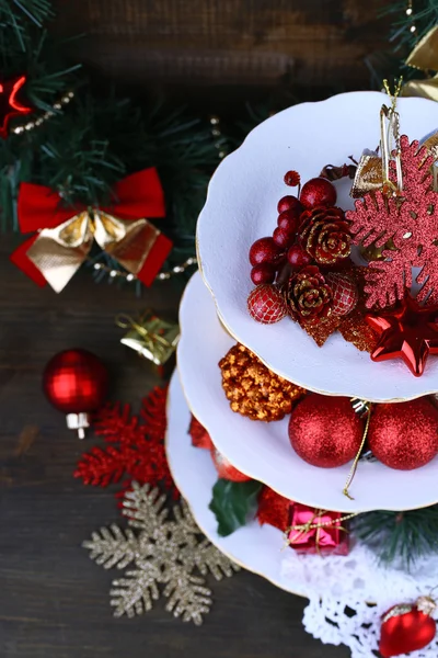 Christmas decorations on dessert stand, on wooden background — Stock Photo, Image