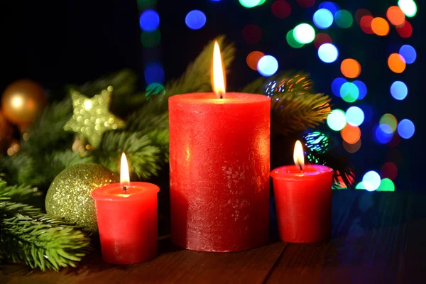 Composition with burning candles, fir tree and Christmas decorations on multicolor lights background — Stock Photo, Image