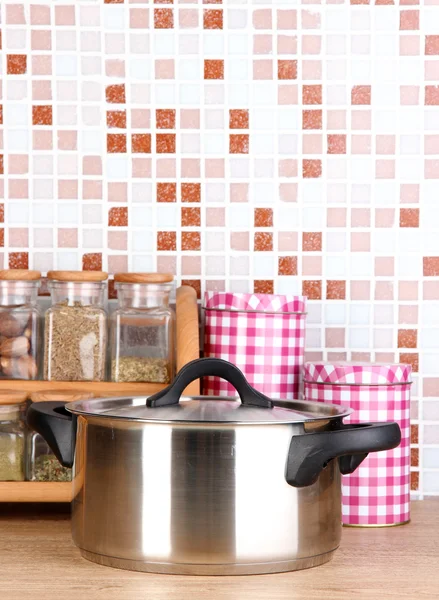 Pote e especiarias na cozinha na mesa em azulejos mosaico fundo — Fotografia de Stock