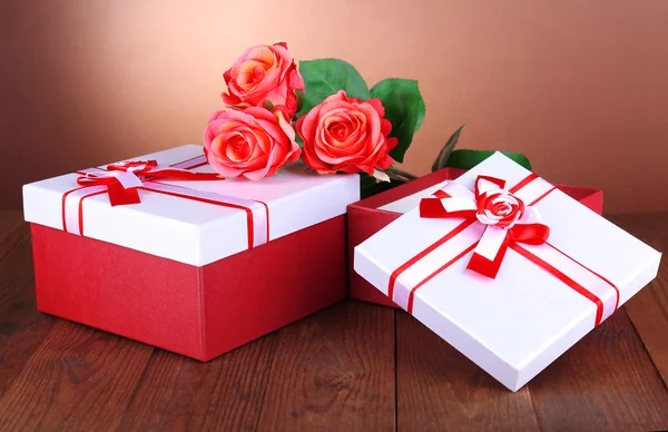 Hermosas cajas de regalo con flores en la mesa sobre fondo marrón —  Fotos de Stock