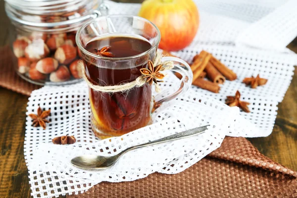 Bevanda calda in tazza di vetro con frutta e spezie, su fondo di legno — Foto Stock