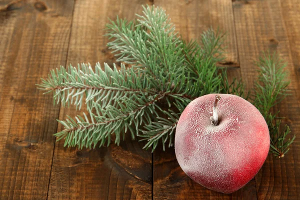 Manzana esmerilada roja con rama de abeto sobre fondo de madera — Foto de Stock