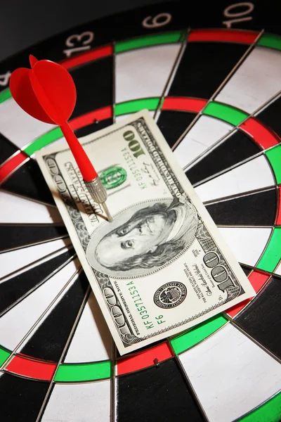 Money pierced by arrow on dartboard close up — Stock Photo, Image