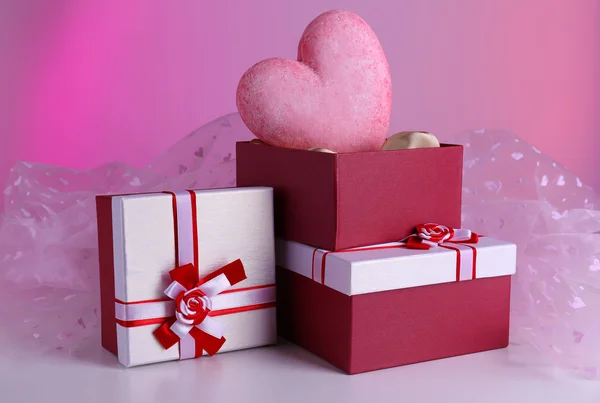 Pile de boîtes-cadeaux et coeur décoratif, sur fond de couleur — Photo
