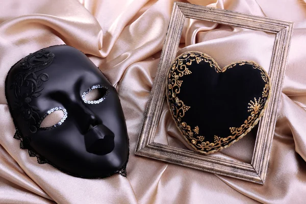 Decorative black heart and mask, on color fabric — Stock Photo, Image