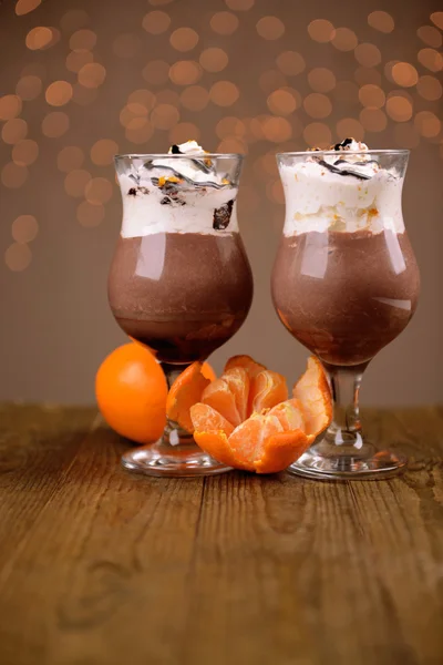 Sobremesa saborosa com chocolate, creme e molho de laranja, na mesa de madeira, no fundo das luzes — Fotografia de Stock