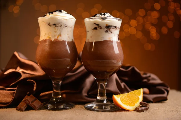 Leckeres Dessert mit Schokolade, Sahne und Orangensoße, auf dem Tisch, auf hellem Hintergrund — Stockfoto