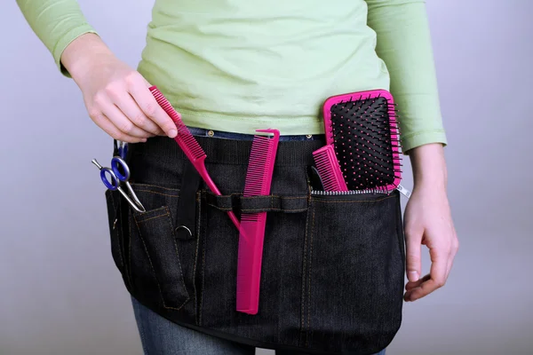 Woman hairdresser with tool belt on grey background — Stock Photo, Image