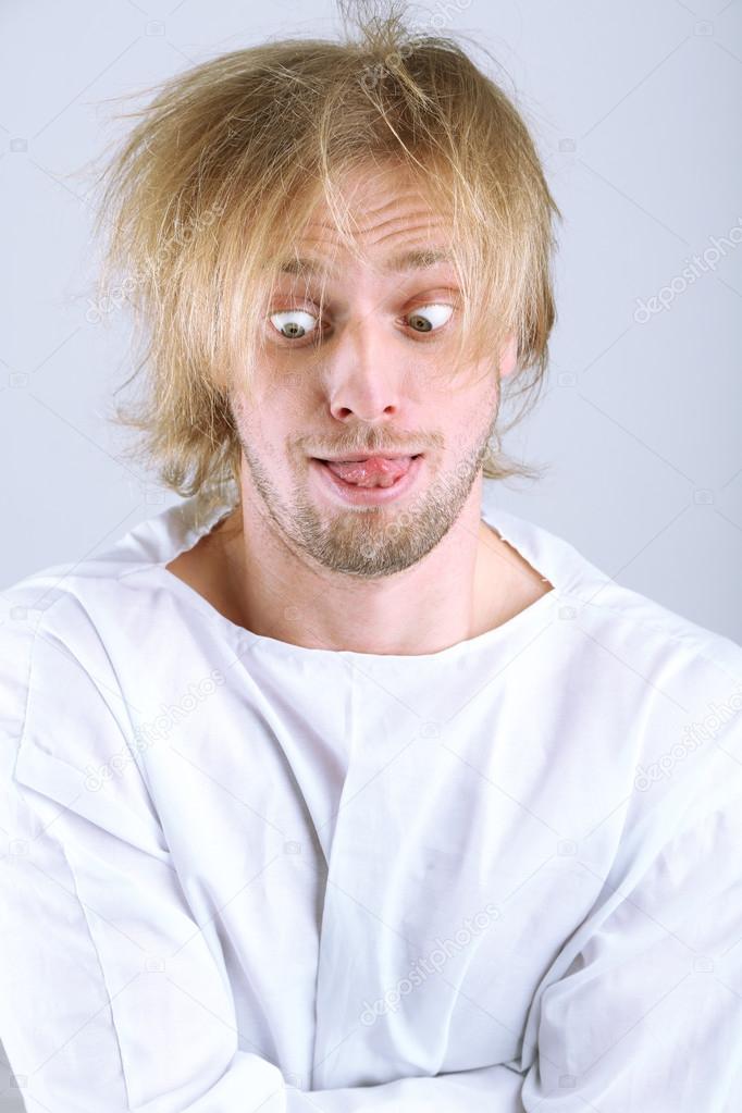 Mentally ill man in strait-jacket on gray background