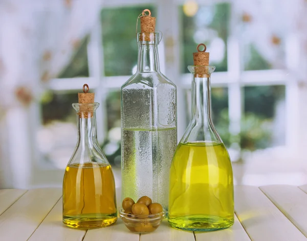 Original glass bottles with salad dressing on wooden table on window background — Stock Photo, Image