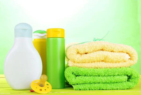 Baby cosmetica en handdoeken op houten tafel, op groene achtergrond — Stockfoto