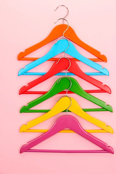 Kleurrijke kleerhangers op roze achtergrond — Stockfoto