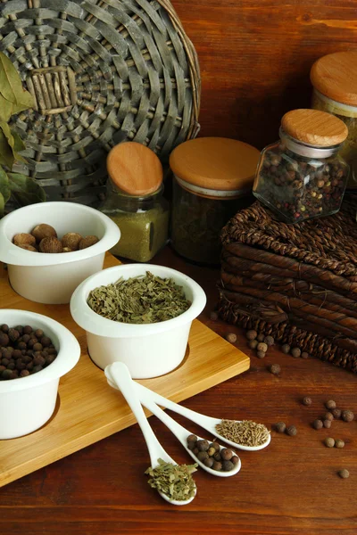 Sortiment av kryddor i vit skedar och skålar, på trä bakgrund — Stockfoto