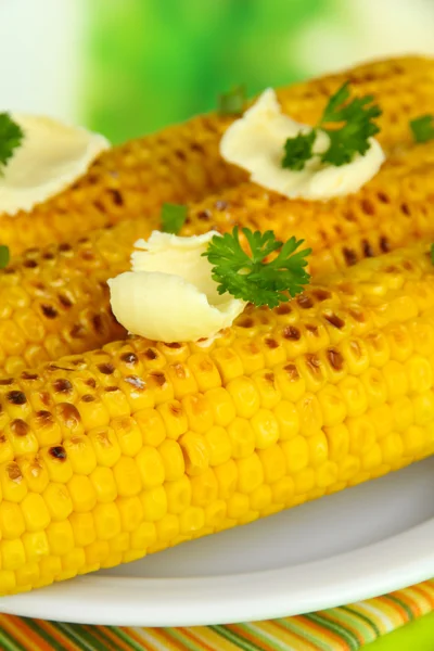 Delicioso maíz dorado a la parrilla con mantequilla en la mesa sobre fondo brillante — Foto de Stock