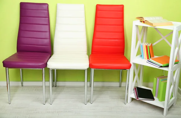 Piękne wnętrza, nowoczesny kolor krzeseł, książki na drewniany stojak, na tle ściany — Zdjęcie stockowe