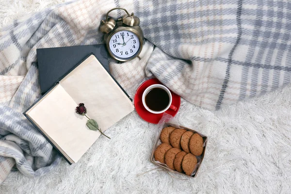 Composición con cuadros calientes, libro, taza de bebida caliente sobre fondo de alfombra de color — Foto de Stock