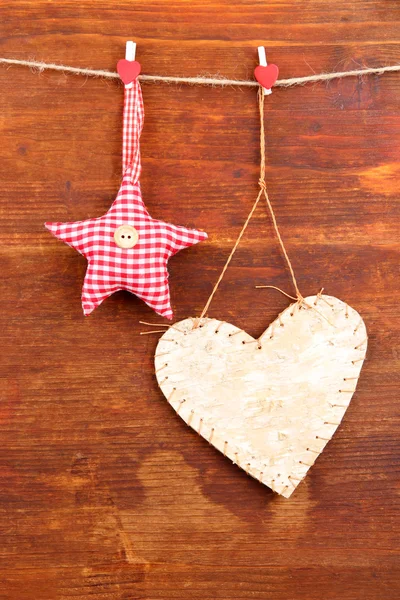 Декоративное сердце и звезда на веревке, на деревянном фоне — стоковое фото