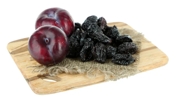 Ciruelas frescas y secas sobre tabla de madera, aisladas sobre blanco — Foto de Stock