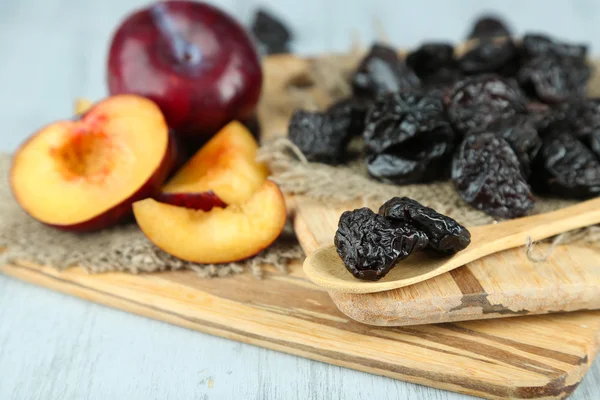 Fresh and dried plums on napkin, on wooden background — Stock Photo, Image