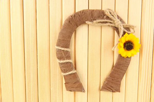 Decoratieve hoefijzer van stro met zonnebloem, op houten achtergrond — Stockfoto