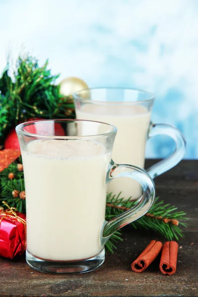 Copos de gemada com ramos de abeto e decorações de Natal na mesa no fundo brilhante — Fotografia de Stock