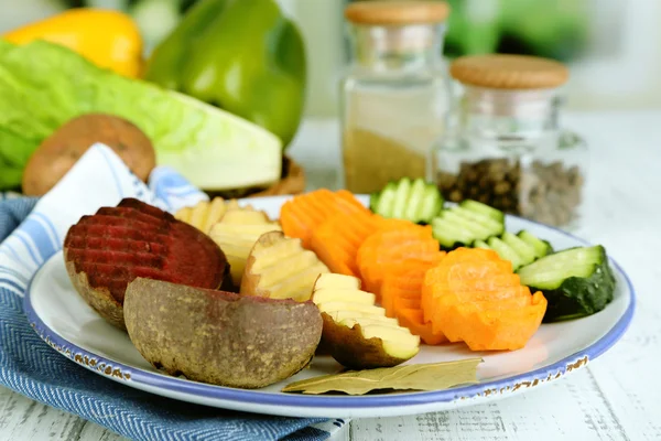 Beautiful sliced vegetables, on plate, on wooden table, on bright background — Stock Photo, Image