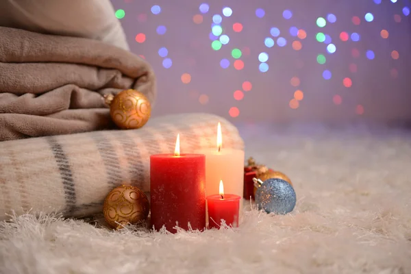 Composition avec plaids, bougies et décorations de Noël, sur tapis blanc sur fond lumineux — Photo