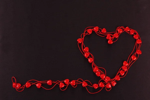 Heart-shaped beads on string on fabric background — Stock Photo, Image