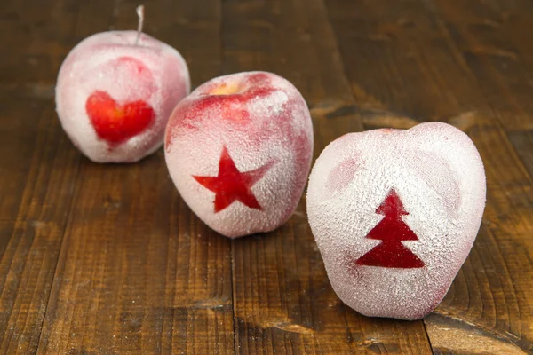 Holiday apples with frosted drawings on wooden background — Stock Photo, Image