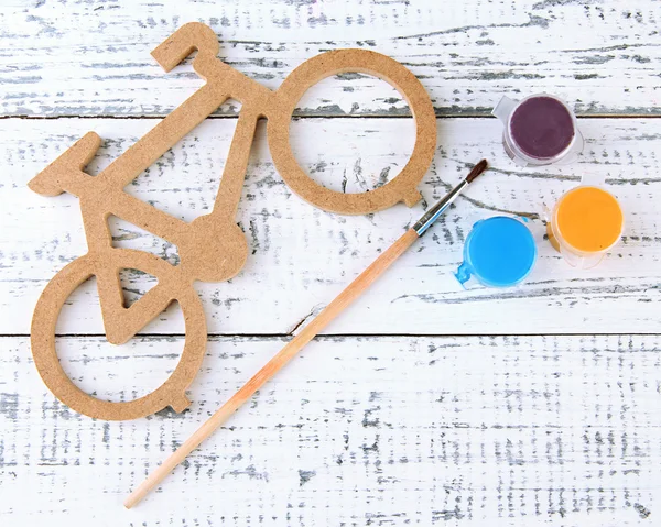 Dekoratives Fahrrad mit Pinsel und Farben auf Holzgrund — Stockfoto