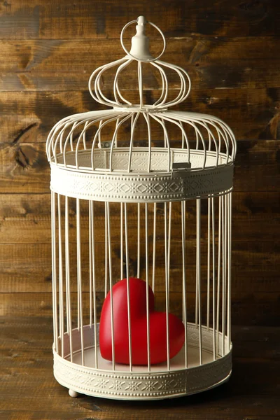 Heart in decorative cage on wooden background — Stock Photo, Image