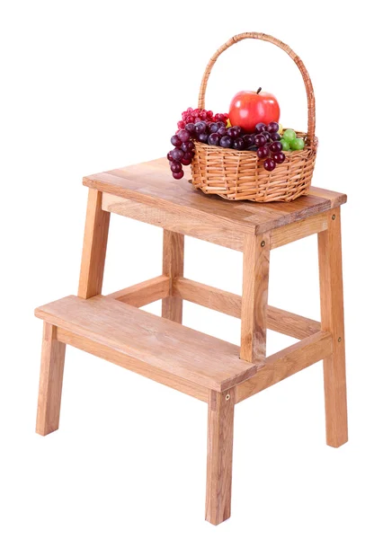 Cesta de mimbre con frutas, en una pequeña escalera de madera, aislada en blanco — Foto de Stock