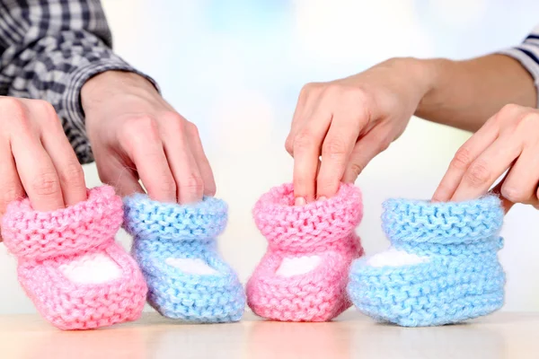 Hands with crocheted booties for baby, on light background — Stock Photo, Image