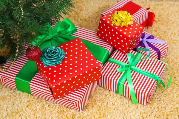 Many colorful presents with luxury ribbons on color carpet background — Stock Photo, Image