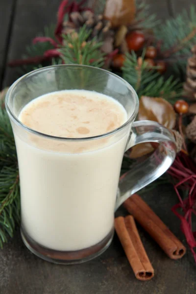 Cup of eggnog with fir branches and Christmas decorations on wooden background — Stock Photo, Image