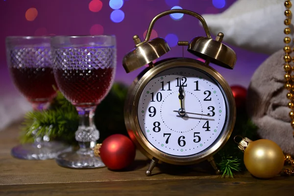 Copos de vinho, despertador retro e decoração de Natal em fundo brilhante — Fotografia de Stock