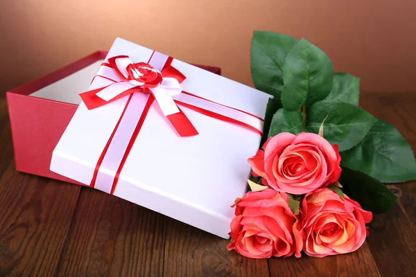 Beautiful gift box with flowers on table on brown background — Stock Photo, Image