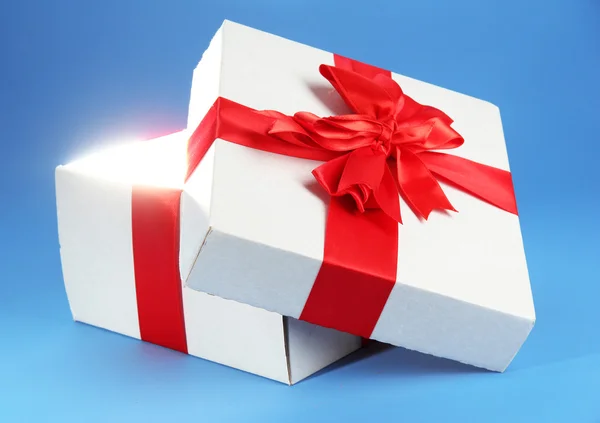 Caja de regalo con luz brillante sobre fondo azul — Foto de Stock