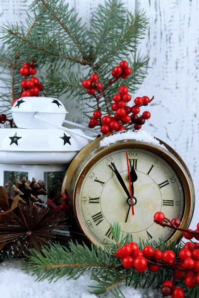 Clock with fir branches and Christmas decorations on table on wooden background — Stock Photo, Image
