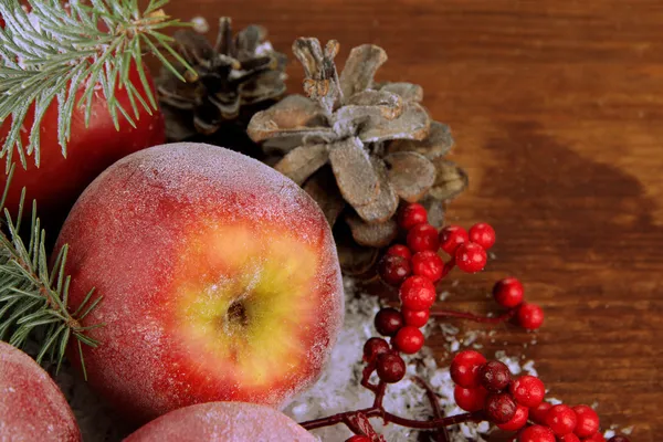 红红的苹果有冷杉的枝和雪地上木制的背景上的浆果 — 图库照片