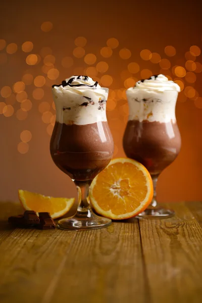 Lekker dessert met oranje, chocolade en crème saus, op houten tafel, op lichten achtergrond — Stockfoto