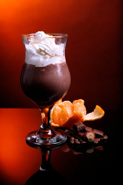 Sabroso postre con chocolate, crema y salsa de naranja, sobre fondo de color oscuro — Foto de Stock