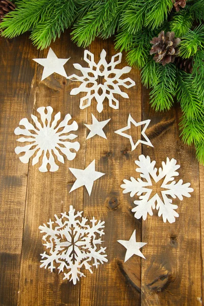 Hermosos copos de nieve de papel con rama de abeto sobre fondo de madera — Foto de Stock